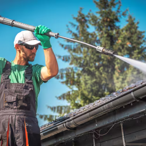 Couvreur appliquant un traitement hydrofuge sur un toit en tuiles pour le protéger de l'humidité